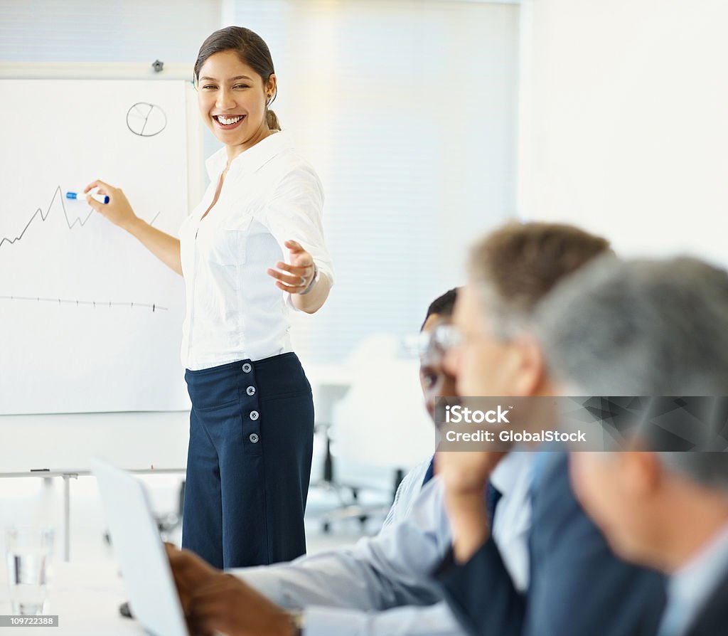 Mujer sonriente dando presentación a un grupo de negocios - Foto de stock de 20 a 29 años libre de derechos