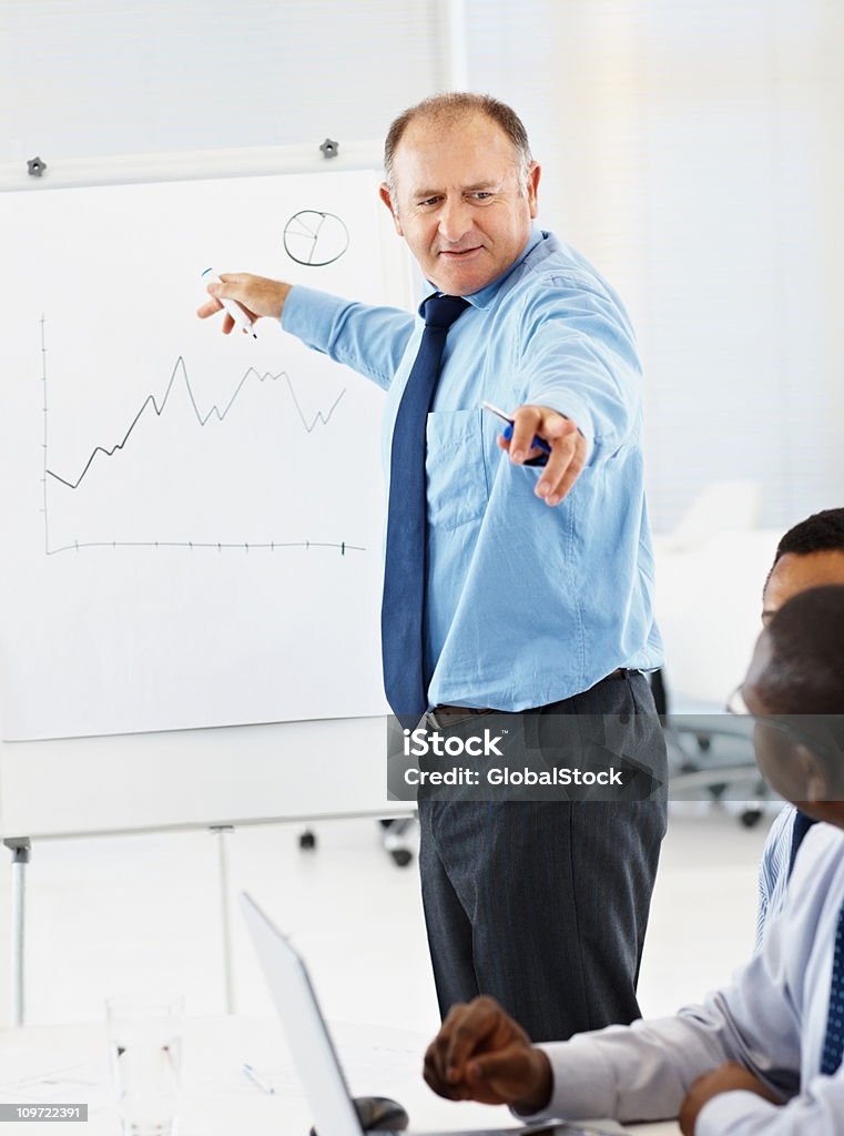 Geschäftsmann zeigt finanzielle Diagramm auf whiteboard zu Kollegen - Lizenzfrei 45-49 Jahre Stock-Foto