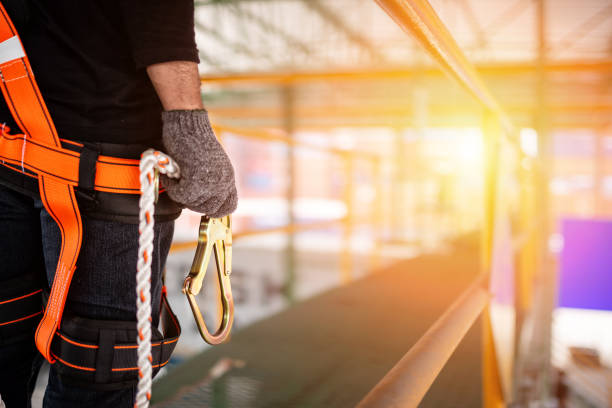 Construction worker wearing safety harness and safety line Construction worker wearing safety harness and safety line working at high place safety harness photos stock pictures, royalty-free photos & images