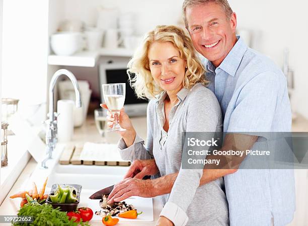 Sorridente Coppia Matura Sorseggiare Un Drink Durante La Preparazione Di Alimenti - Fotografie stock e altre immagini di Bottiglia di vino