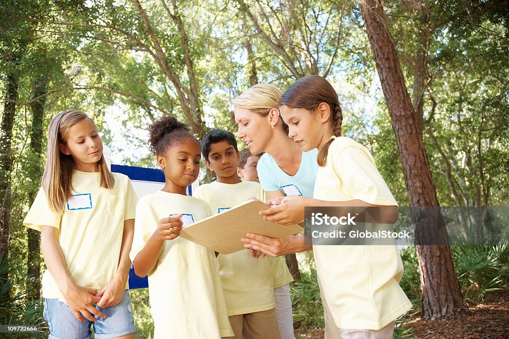 Enseignant avec ses étudiants parler de quelque chose de croquis de réservation - Photo de Forêt libre de droits