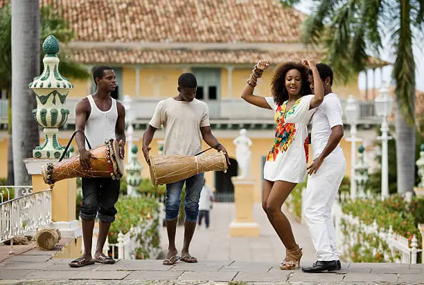 Young black couple dancing salsa on the streets of Trinidad, Cuba while the drummers watching them.