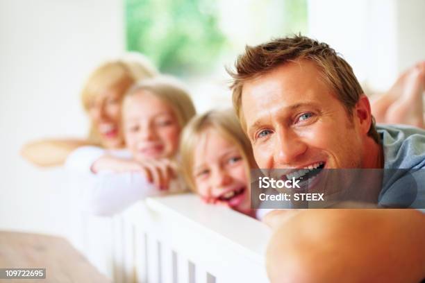 Cheerful Man Lying In Bed With His Family Stock Photo - Download Image Now - 20-29 Years, 30-39 Years, Adult