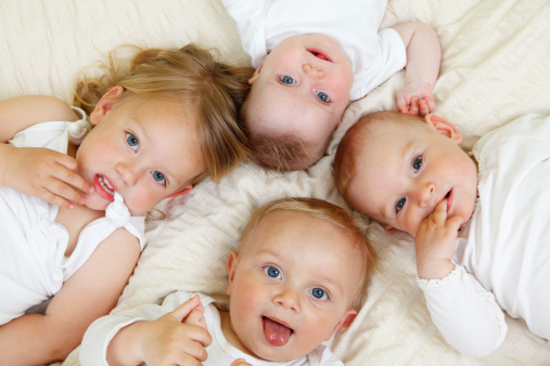 Four small children lying on a bed.