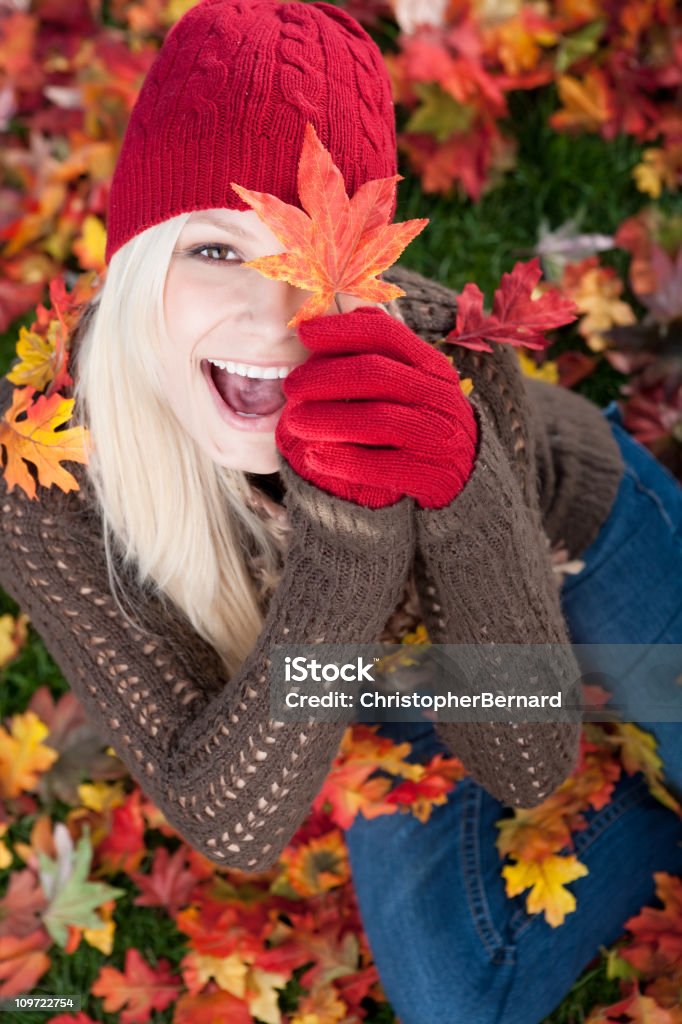 Giovane caucasico bionda donna giocando con foglie di autunno - Foto stock royalty-free di Autunno