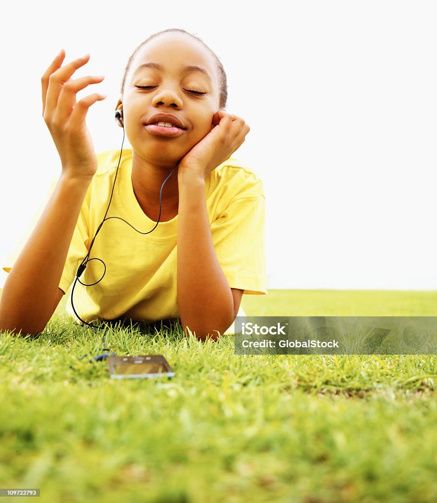 Femme profitant de la musique tout en vous allongeant sur de l'herbe - Photo de Activité de loisirs libre de droits