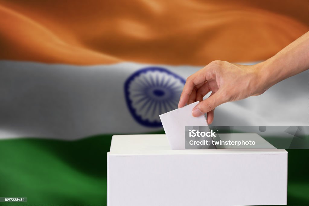 Primer plano de la mano humana casting e insertar un voto y elegir y decidir lo que quiere en la caja de votación con la bandera India mezclado en el fondo. - Foto de stock de India libre de derechos
