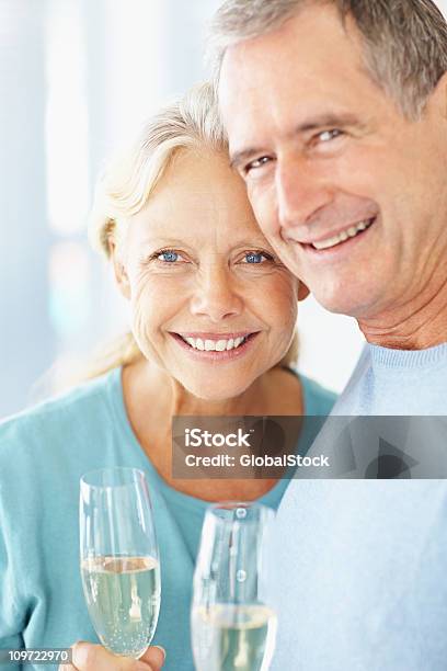 Foto de Detalhe De Um Feliz Aposentado Casal Segurando Copos De Champanhe e mais fotos de stock de Terceira idade