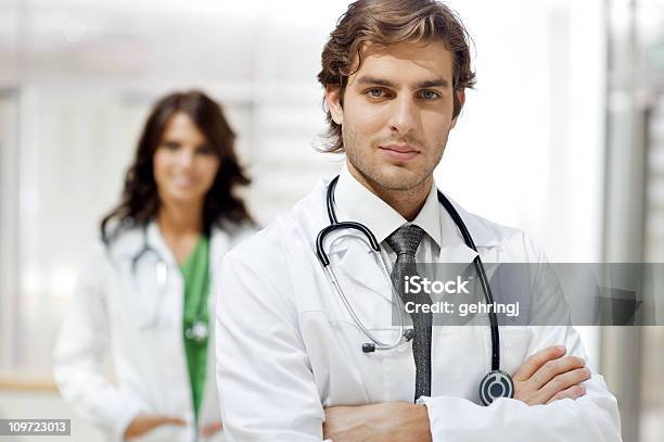 Young Doctor With Colleague In The Background Stock Photo - Download Image Now - Female Nurse, Lab Coat, Smiling