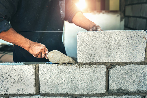 Worker building wall bricks with cement