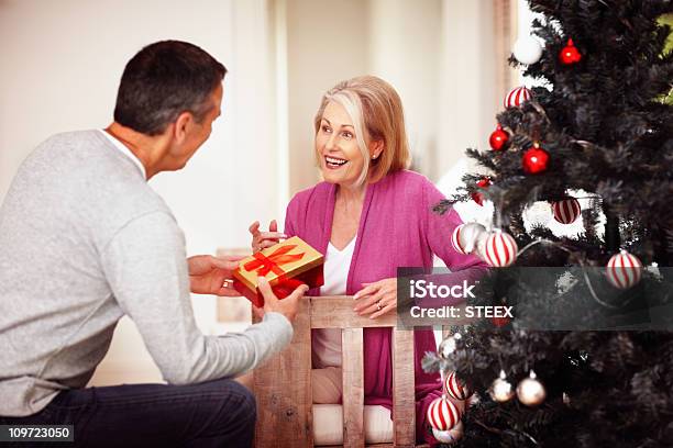 Uomo Maturo Dando Un Regalo Di Natale Per Moglie A Casa - Fotografie stock e altre immagini di Abbigliamento casual