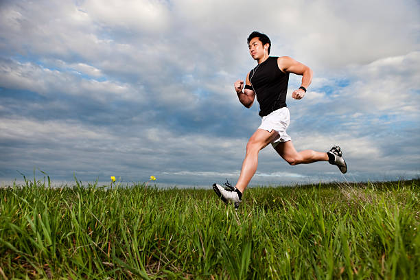 asiatische fitness mann läuft über feld - langstreckenlauf stock-fotos und bilder