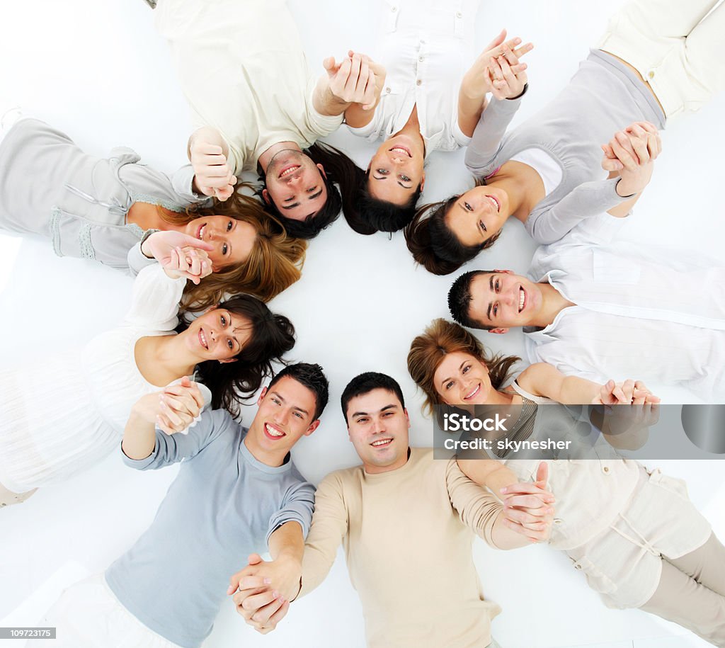 Jóvenes están recostadas en un círculo con las manos unidas. - Foto de stock de Círculo libre de derechos