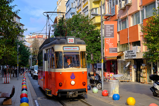 Old yellow trams in Milan, Italy. A corridor of trees in the city.