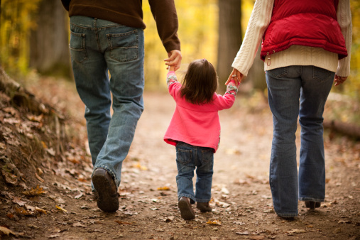Family of Three Walking on Trail Through Autumn Woods