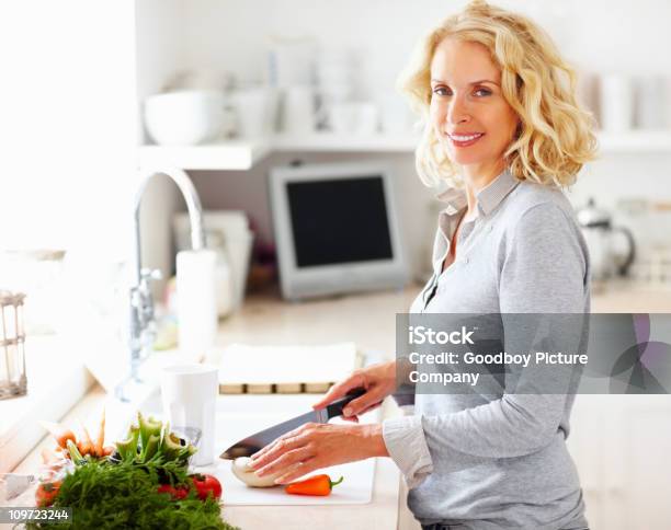 Medio De Mujer Verduras De Corte En La Cocina Foto de stock y más banco de imágenes de Mujeres - Mujeres, Vegetal, Adulto maduro
