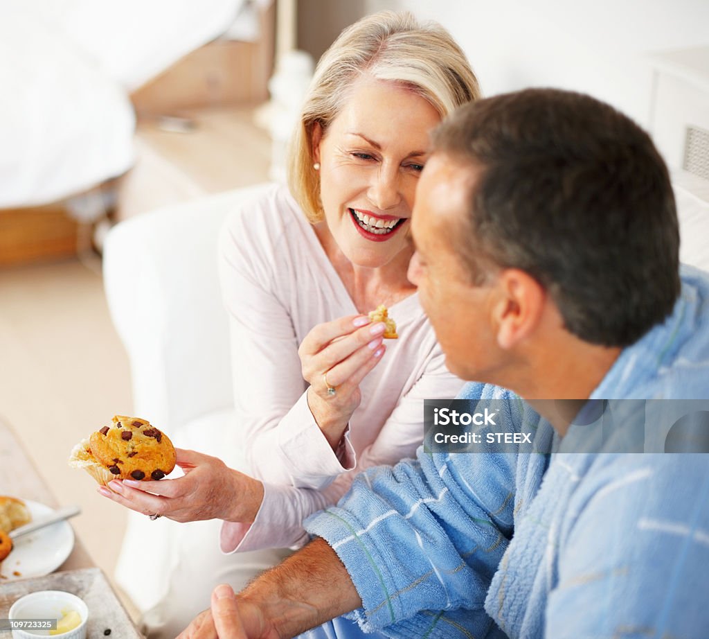 Joyeuse femme d'âge mûr manger un Muffin à mari - Photo de Manger libre de droits