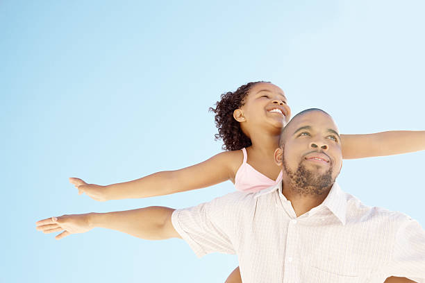 istock Girl on her dad's back both with arms out under clear sky 109723348