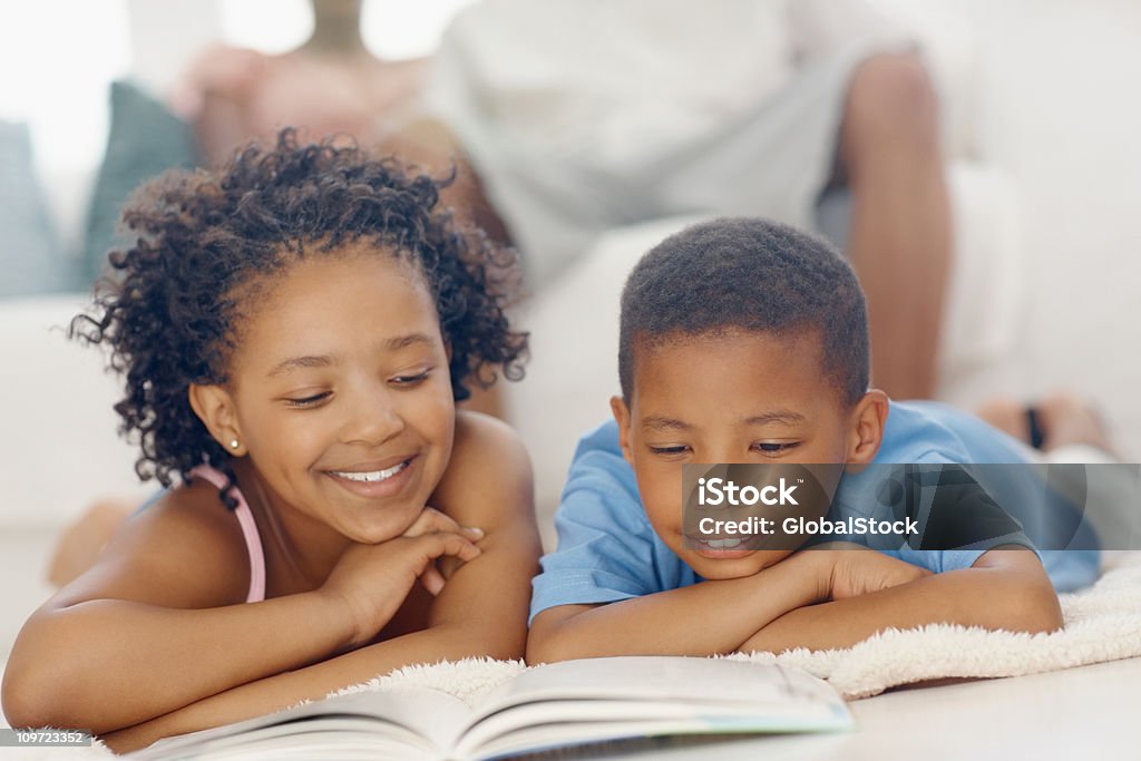 Crianças lendo livro com os pais no fundo - Foto de stock de Ler royalty-free
