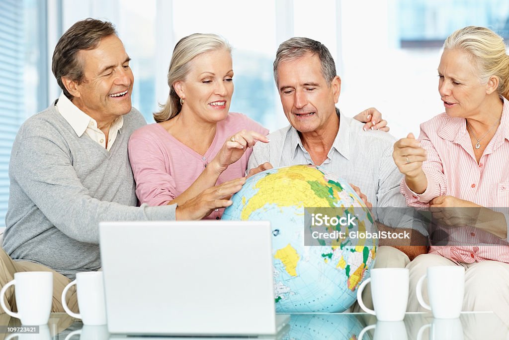 Mujeres maduras y hombres mayores mirando globo - Foto de stock de 50-59 años libre de derechos