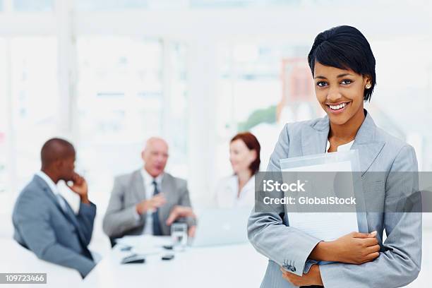 Young Businessfrau Mit Ordner Und Ihr Team Im Hintergrund Stockfoto und mehr Bilder von Afro-amerikanischer Herkunft