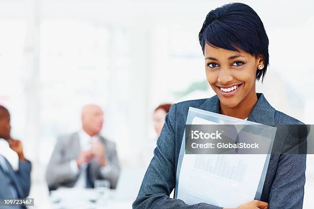 Young Business Female Holding Folder With Her Team In Background Stock Photo - Download Image Now