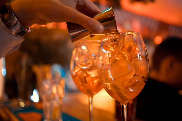istock Bartender garnishing on the counter three Spritz, a classic refreshing Italian aperitif made mixing Aperol, Prosecco and sparkling soda to enjoy with friends and family at the bar before meals. 1097236232