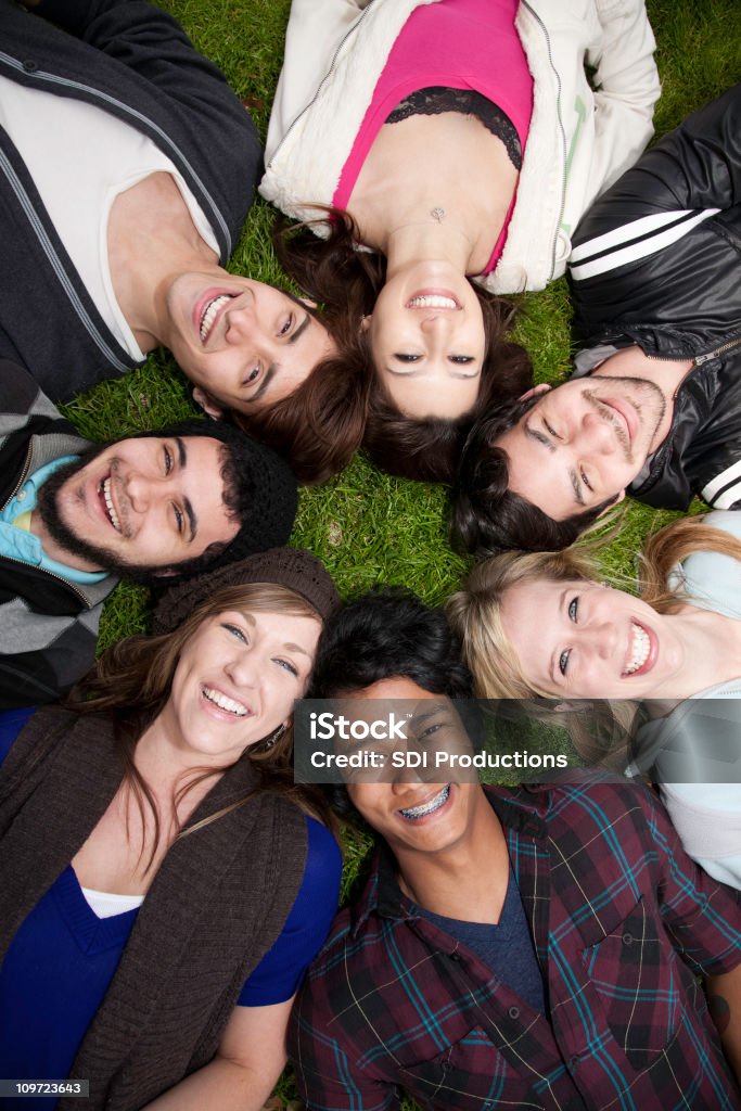 Junge Erwachsene liegen in einem Kreis auf dem Rasen - Lizenzfrei Frauen Stock-Foto