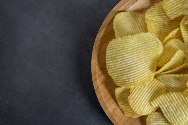 istock Plate of crispy potato chips on stone background 1097237900