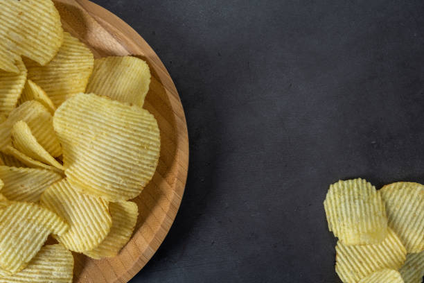 istock Plate of crispy potato chips on stone background 1097238270