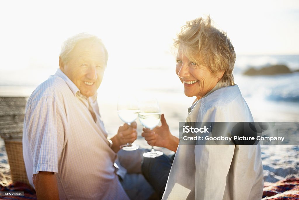 Vecchia coppia di bere vino bianco durante un picnic sulla spiaggia - Foto stock royalty-free di 70-79 anni