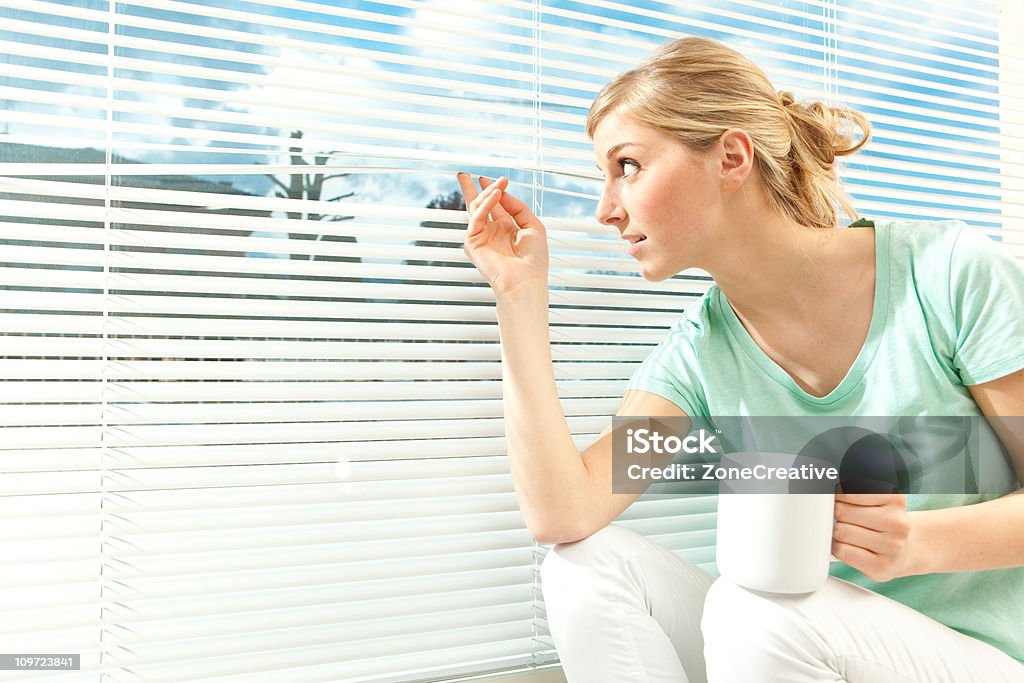 Schönes Blondes Mädchen schaut aus dem Fenster mit cup - Lizenzfrei Attraktive Frau Stock-Foto