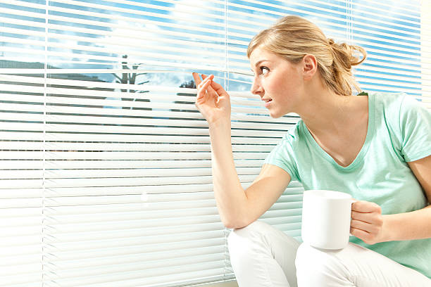 istock beautiful blond girl peeks from a window with cup 109723841