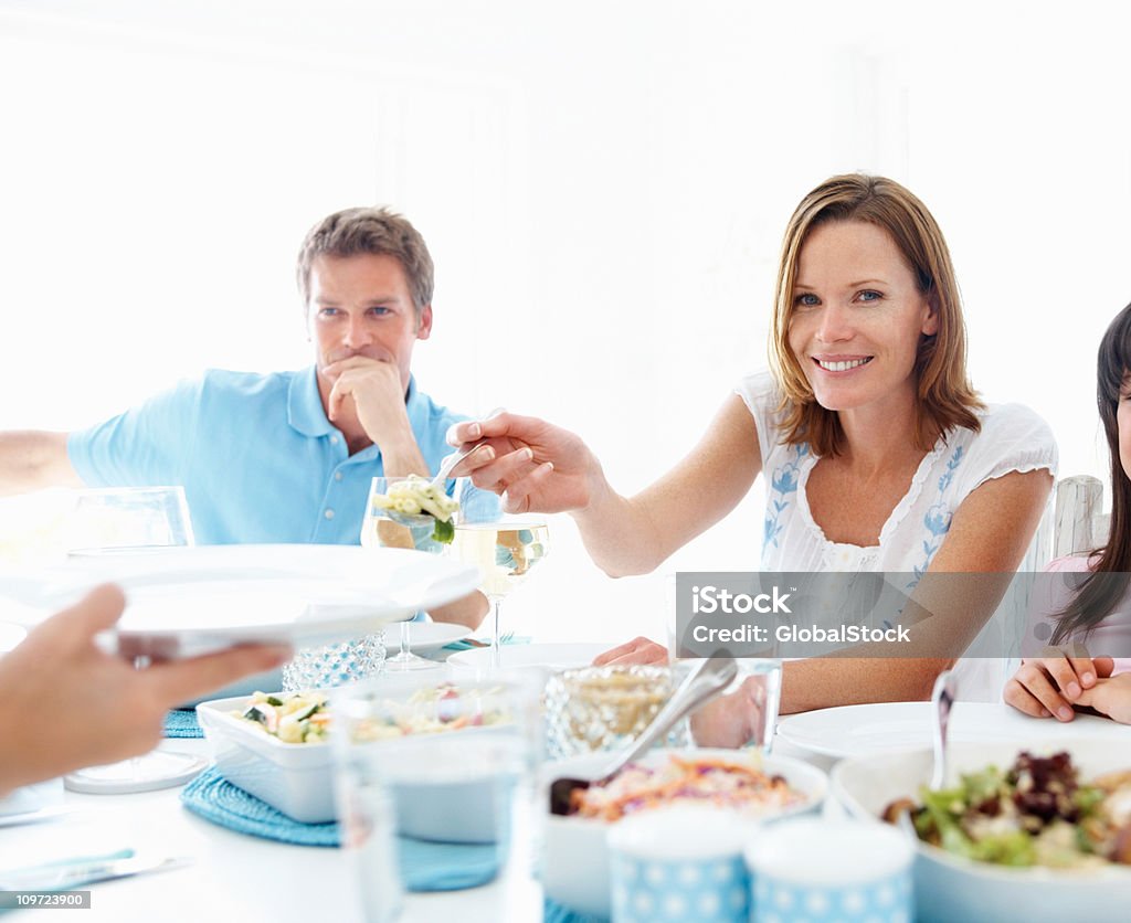 Jeune femme, qui sert des plats en famille après avoir déjeuner - Photo de Activité de loisirs libre de droits