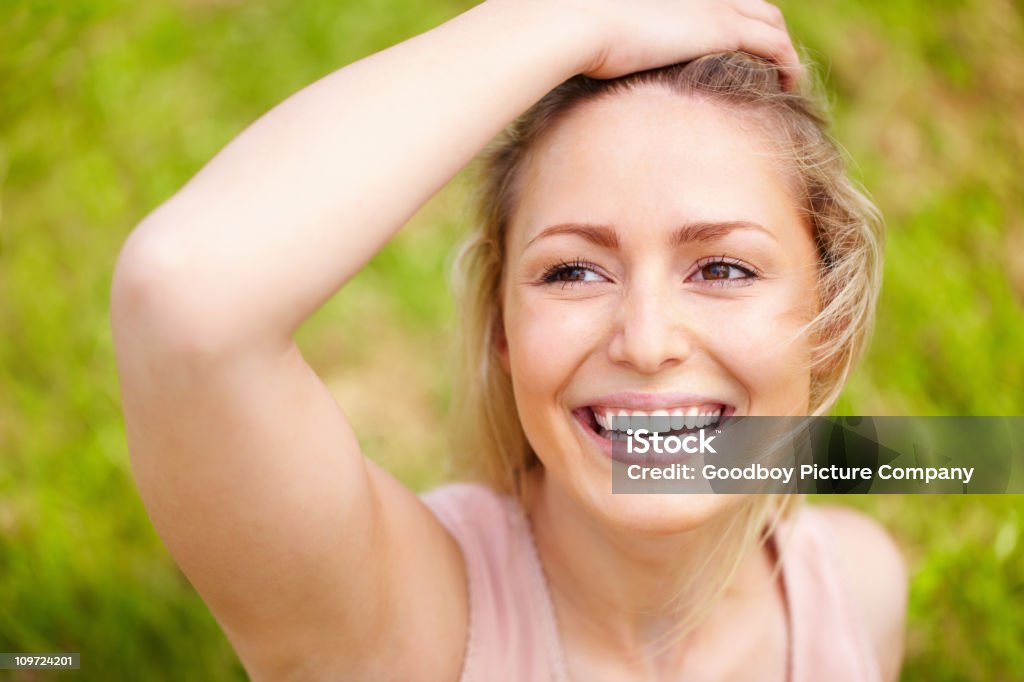 Radosny Młoda kobieta z ręki na głowie na zielonym tle - Zbiór zdjęć royalty-free (20-29 lat)