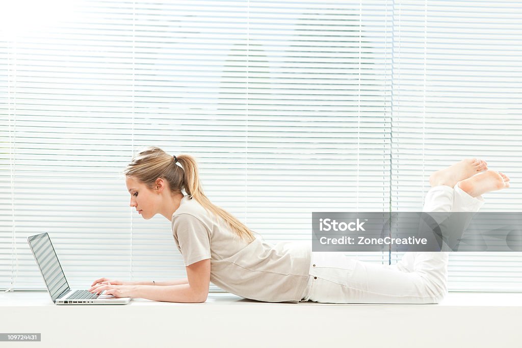Giovane bella ragazza lavora con computer portatile - Foto stock royalty-free di Abbigliamento casual