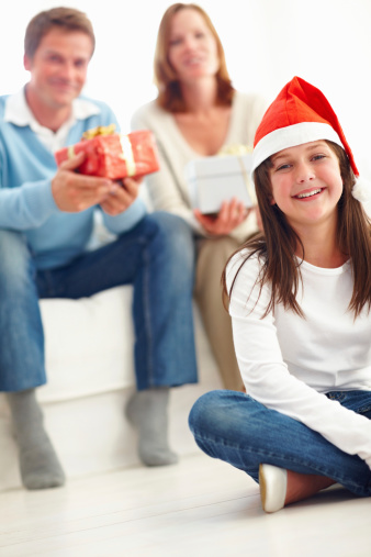 Cute little girl sitting in the floor with parents at the background