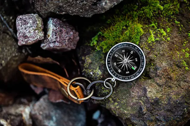 Photo of Compass with leather keychain on rock natural background Using wallpaper or background travel or navigator image