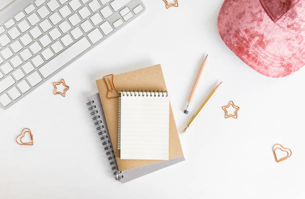 istock Flat lay top view notepad girly mockup: pencils,photo camera, pink hat and keyboard on white background. Clean and bright. Travel concept. Text space 1097247190