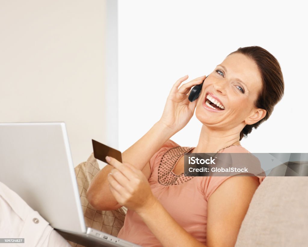 Alegre hablando por teléfono móvil mientras usando computadora portátil - Foto de stock de 30-39 años libre de derechos