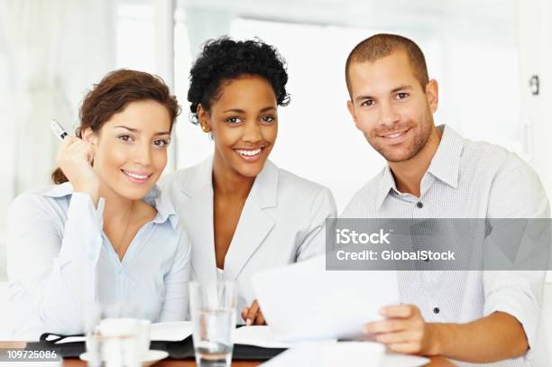 Retrato De La Sonriente Colegas De Negocios Con Documentos En El Lugar De Trabajo Foto de stock y más banco de imágenes de 20-24 años