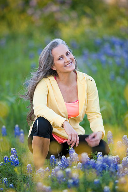 frau sitzt in feld von bluebonnets - lupine single flower flower blue stock-fotos und bilder