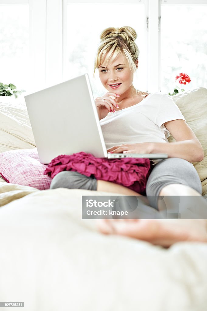 Confortável e informal mulher com o laptop na cama - Foto de stock de 25-30 Anos royalty-free