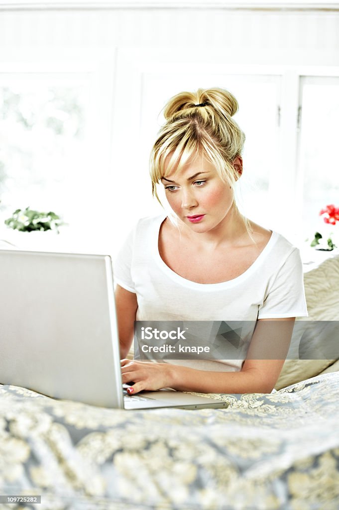 Comfortable casual woman with laptop in bed  25-29 Years Stock Photo