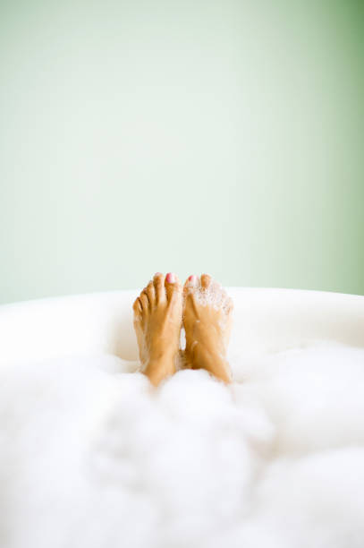 woman's feet emerging in bubble bath - bad fotos stockfoto's en -beelden