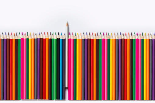 Multi coloured pencils against one white pencil.