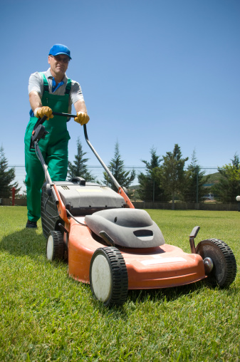 Male gardener working with lawn mower.