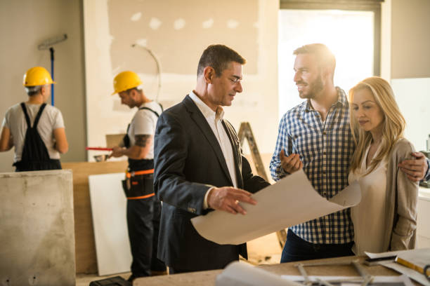 istock Happy couple and building contractor talking about housing plan at construction site. 1097255606