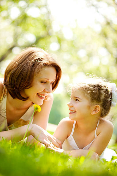 istock Mother and daughter lying on grass in park 109725677