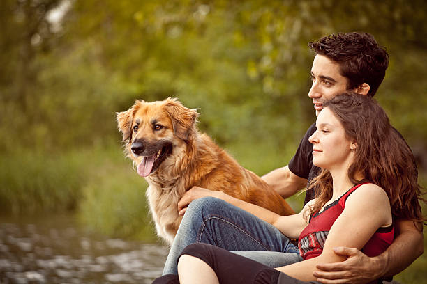 Couple in love with dog in outdoor river with bridge